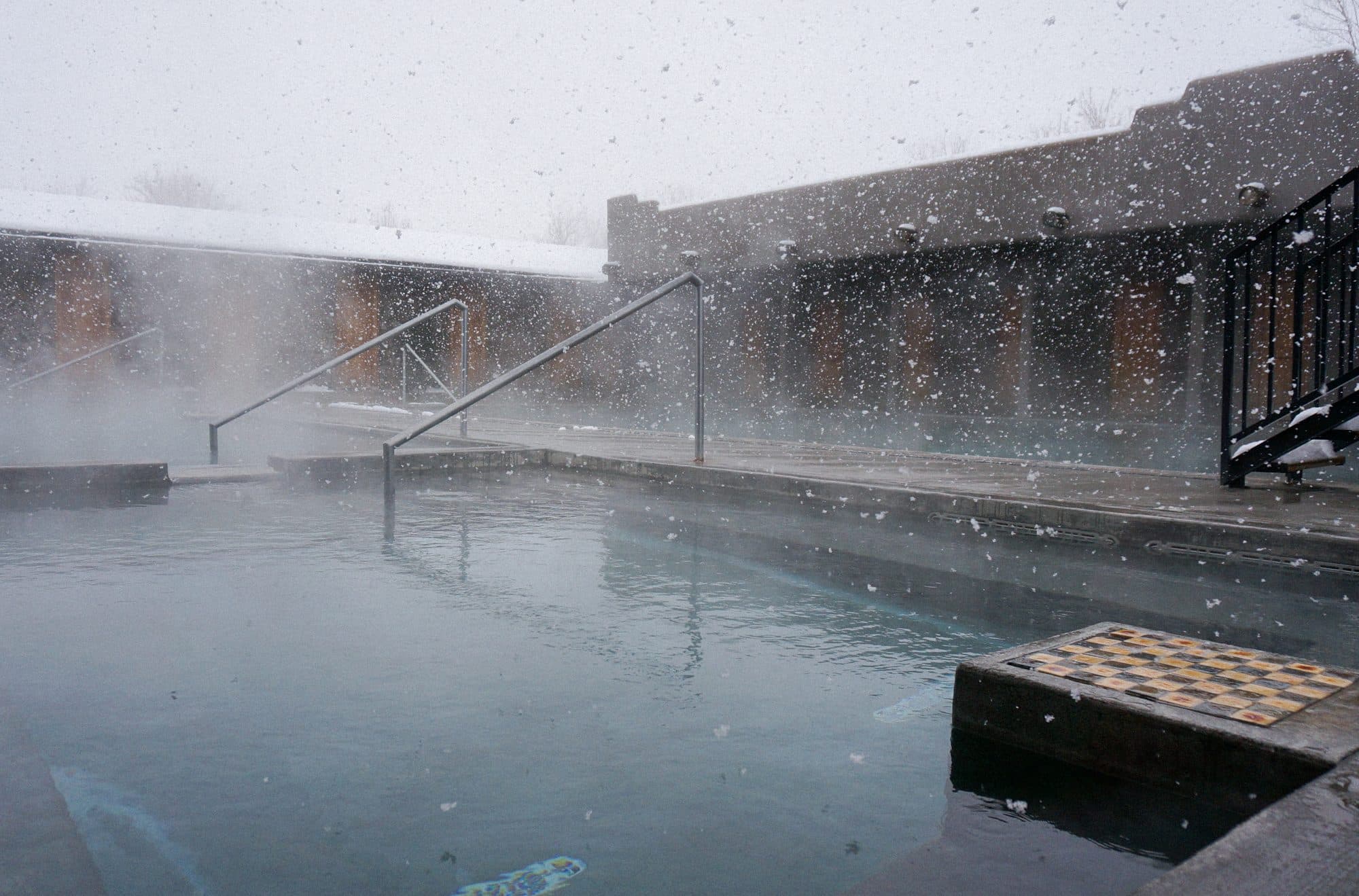 Steaming hot spring pool with snow on the banks at Miracle Hot Springs